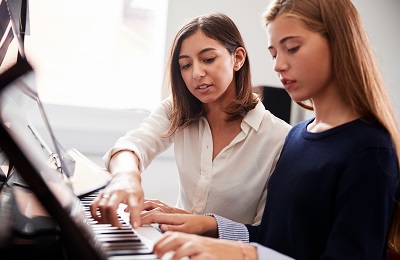 piano teacher adn student sitting at a piano